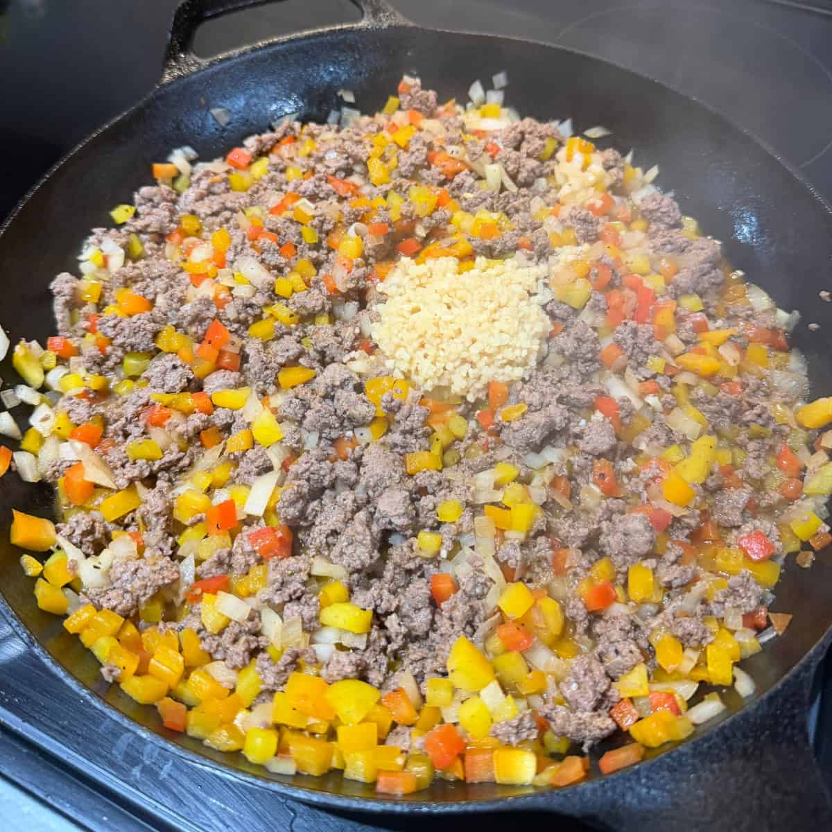 Cooked ground beef, onions, peppers, garlic in skillet