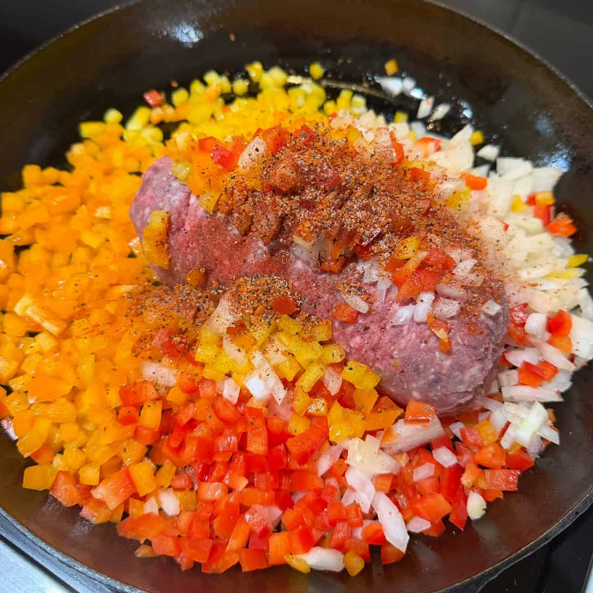 Ground beef, onions, peppers, seasonings in a skillet
