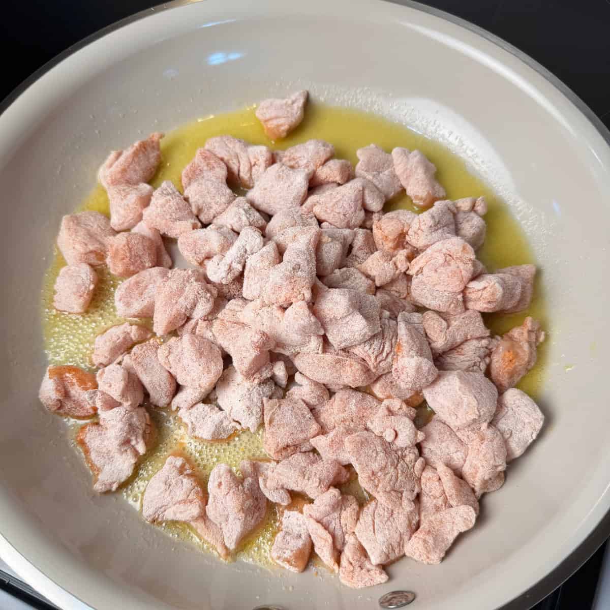 Raw breaded chicken in a pan with oil and butter
