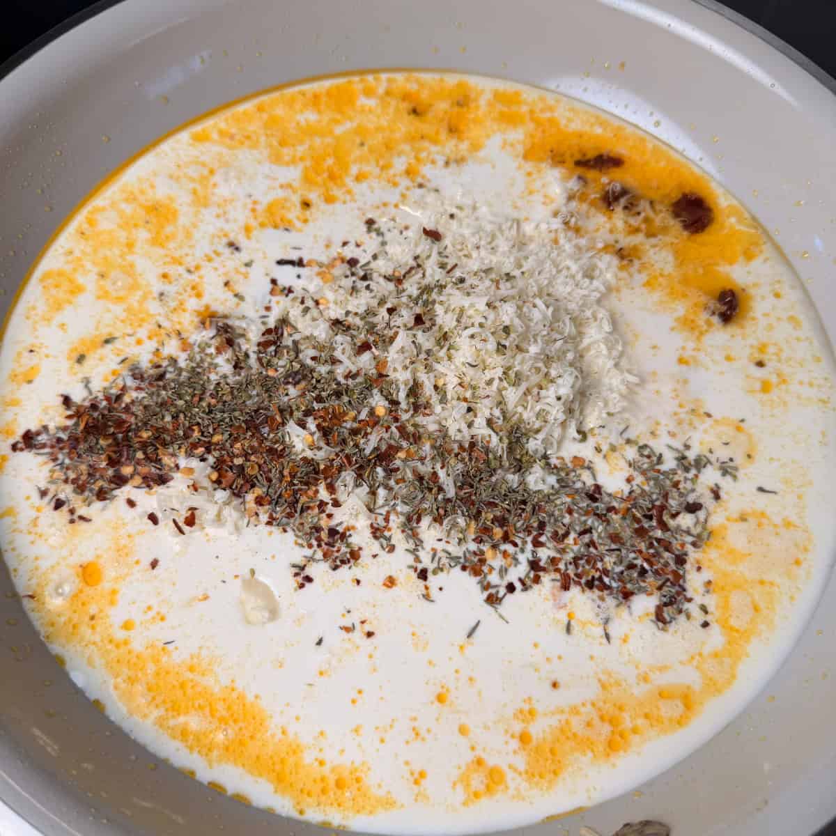Heavy cream, seasonings, Parmesan cheese in a pan