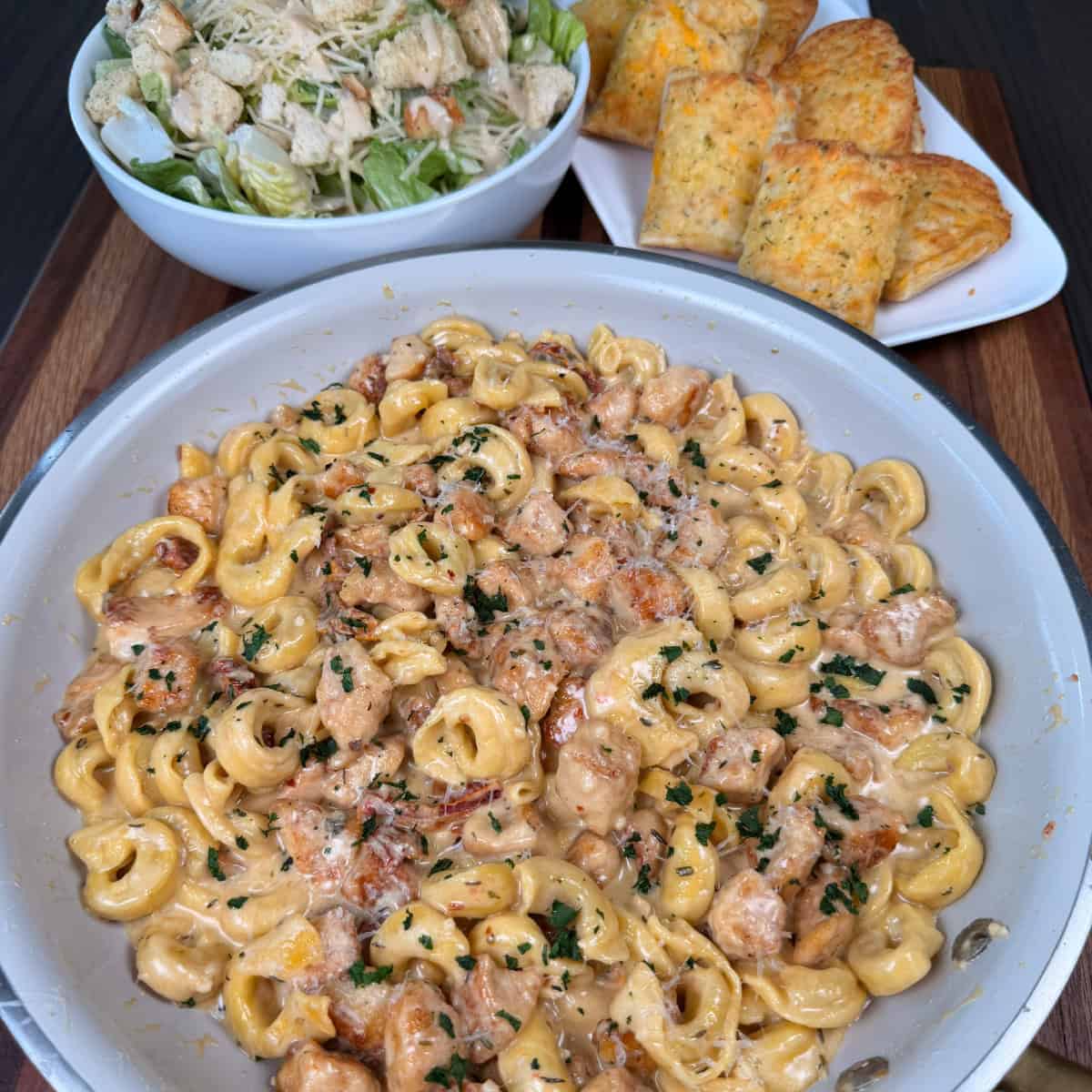 Creamy Chicken and Tortellini in a pan with salad and garlic bread