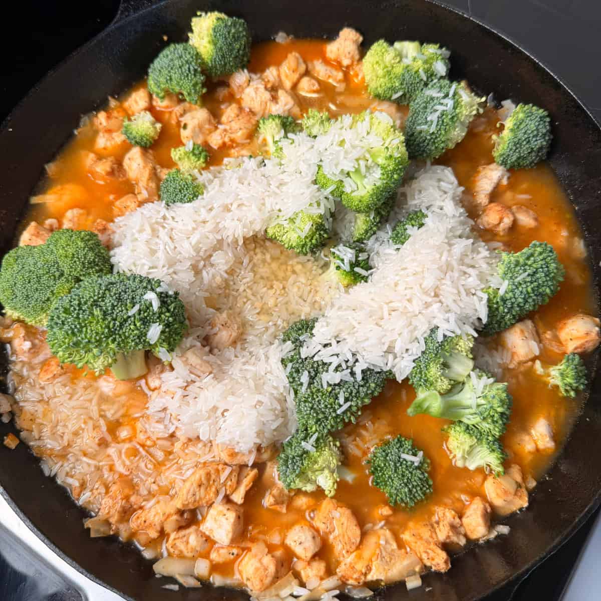 Broccoli, chicken, rice, chicken broth in skillet