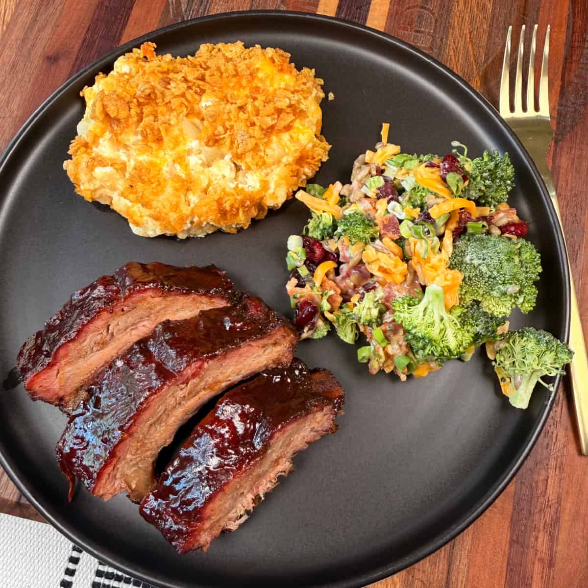 Plated Baby Back Ribs with funeral potatoes and broccoli salad.