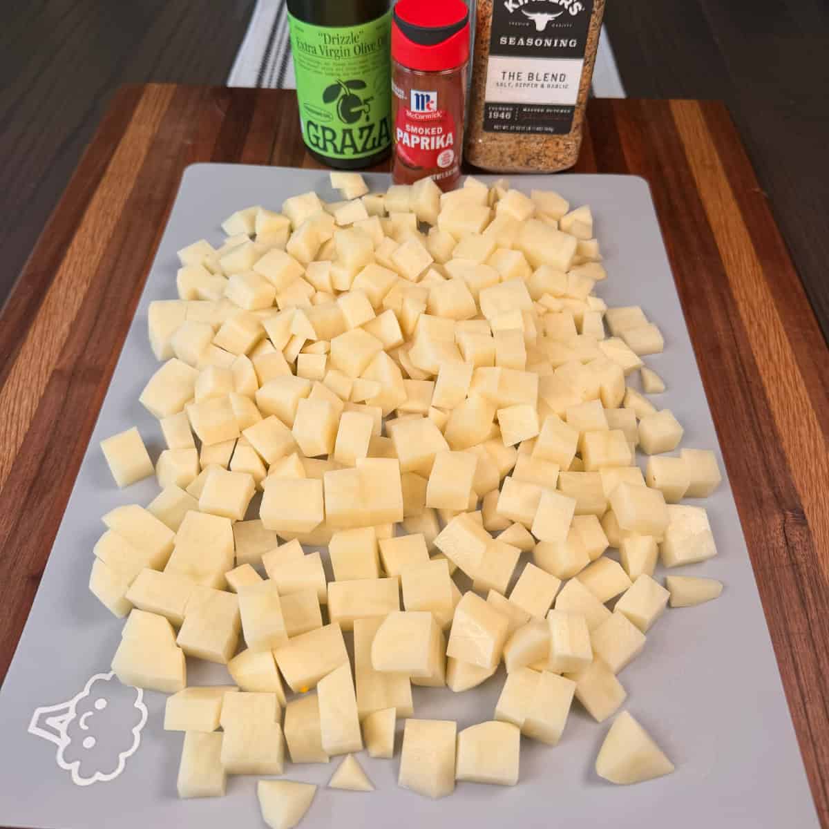 Chopped potatoes with oil and seasonings on cutting board