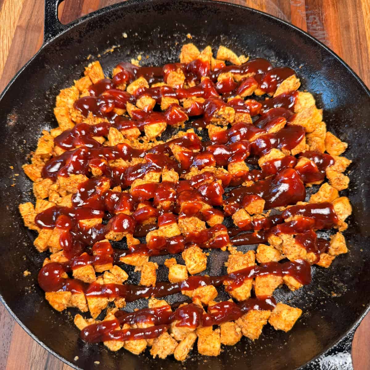 Cooked chicken with BBQ sauce in skillet