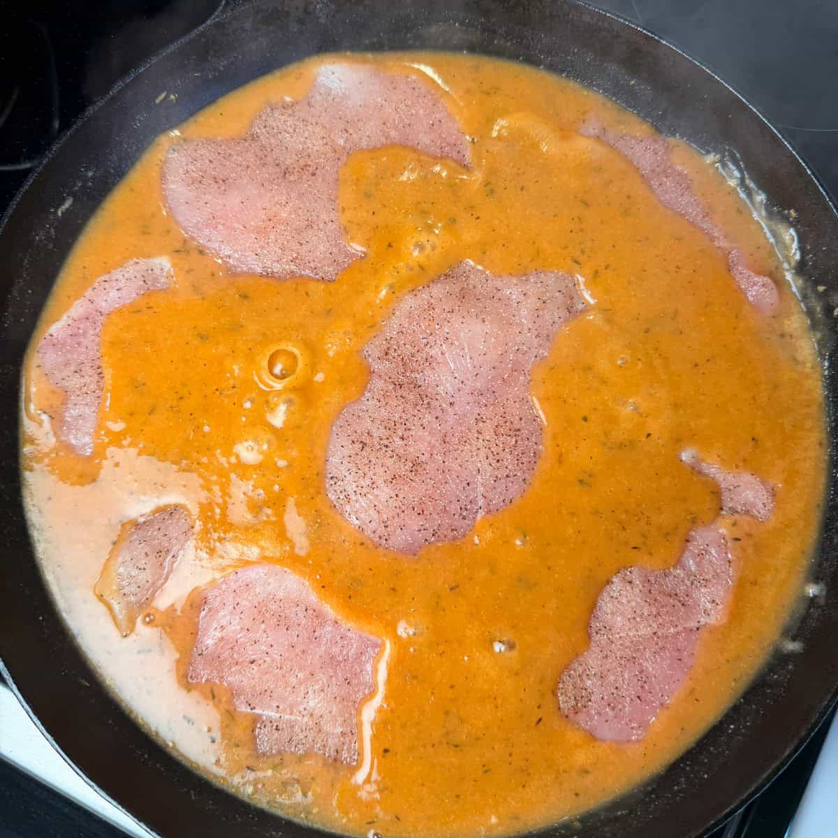 Chicken placed in gravy in skillet