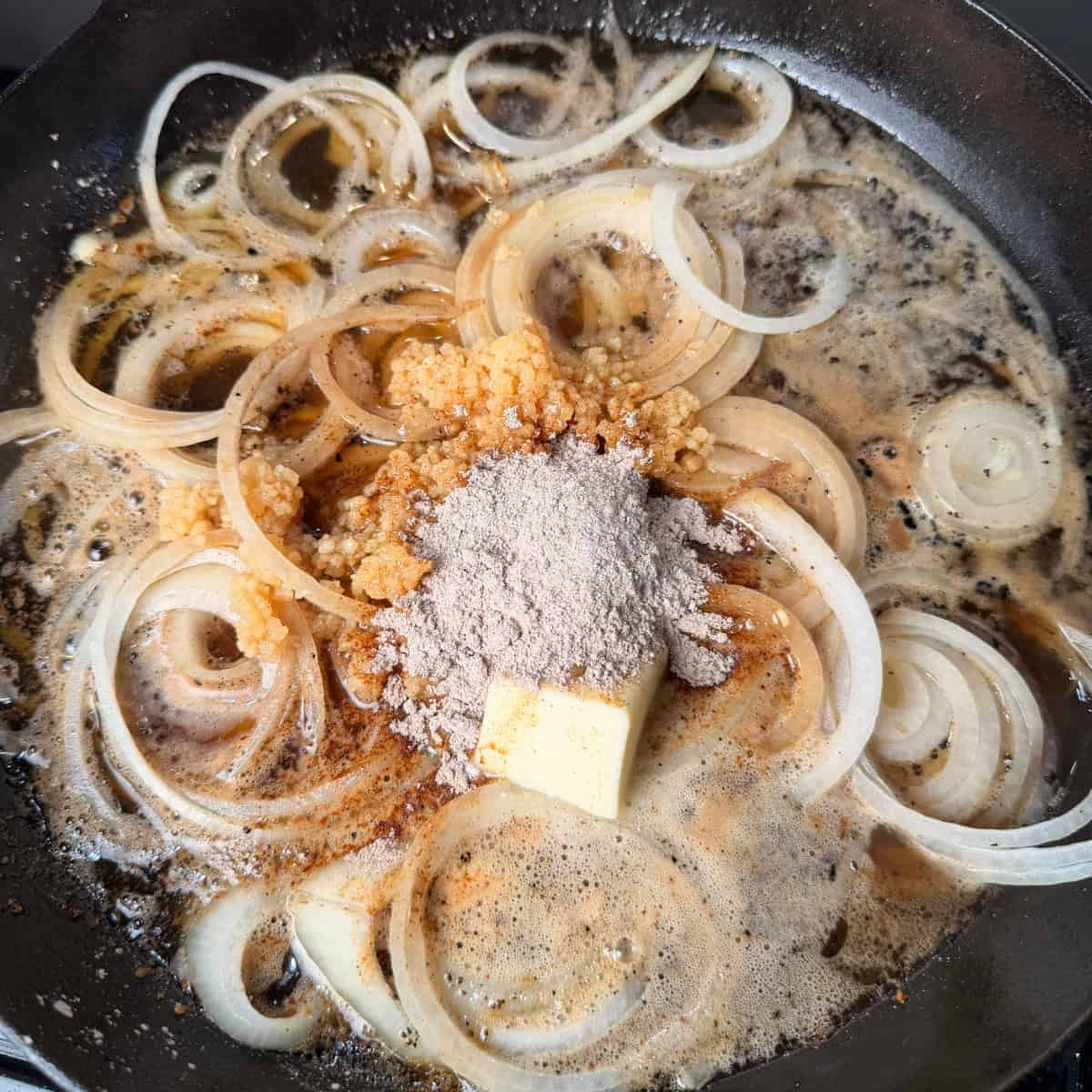 Onions, beer, beef broth, garlic, butter, and seasonings in cast iron skillet