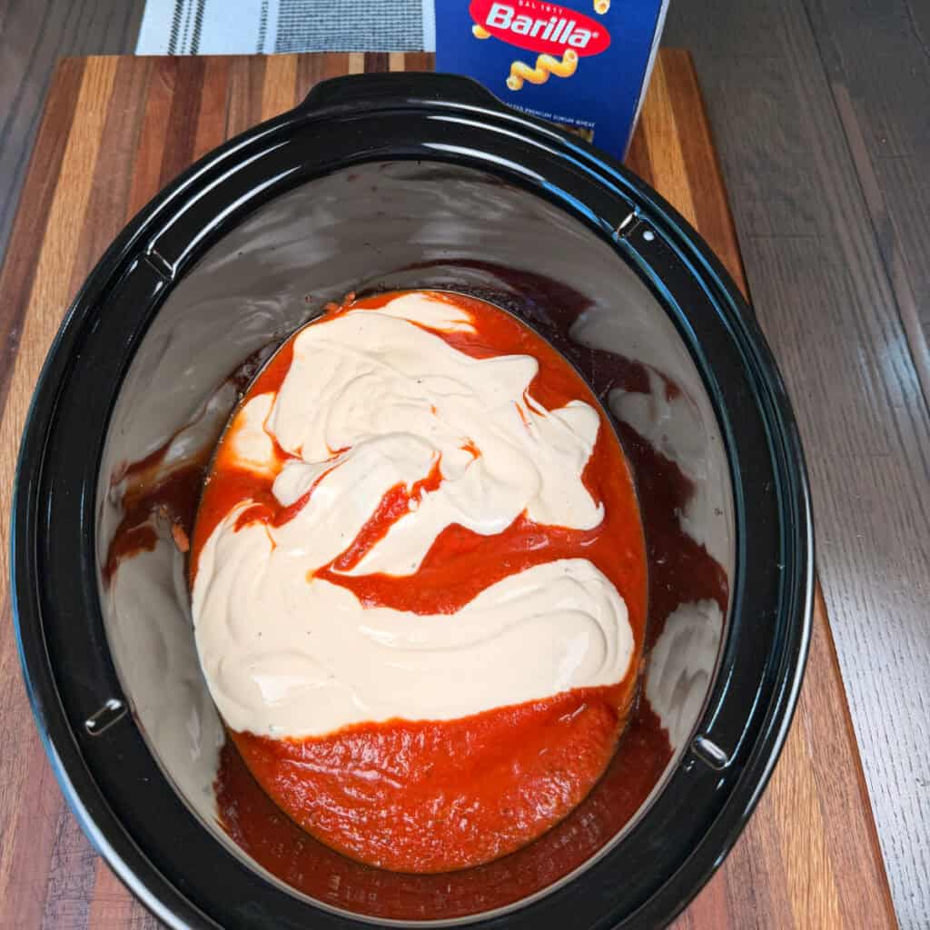 Crockpot with uncooked chicken, marinara, and Alfredo sauce