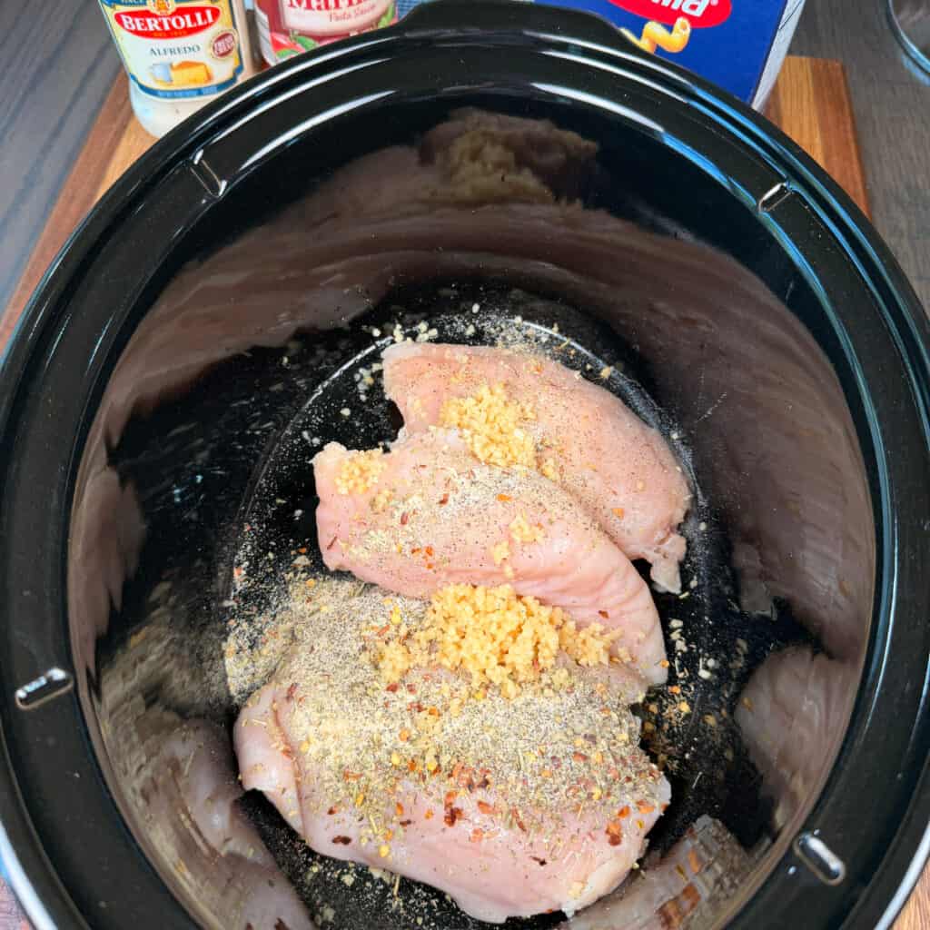Crockpot with seasoned chicken and garlic