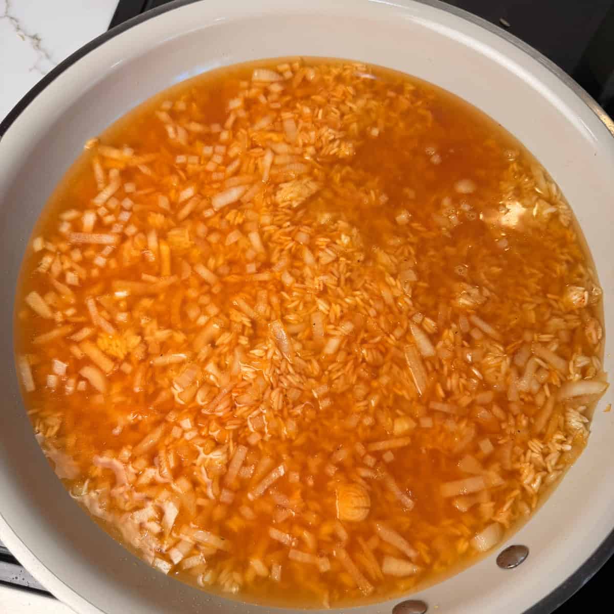 Skillet of rice, onions, tomato bouillon, chicken broth
