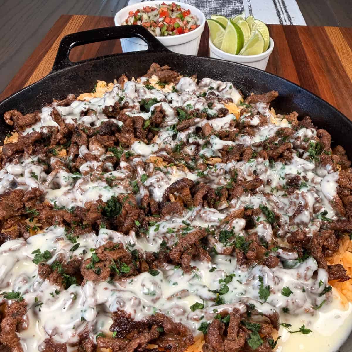 Steak Cheese and Rice Skillet with Pico de Gallo and sliced limes