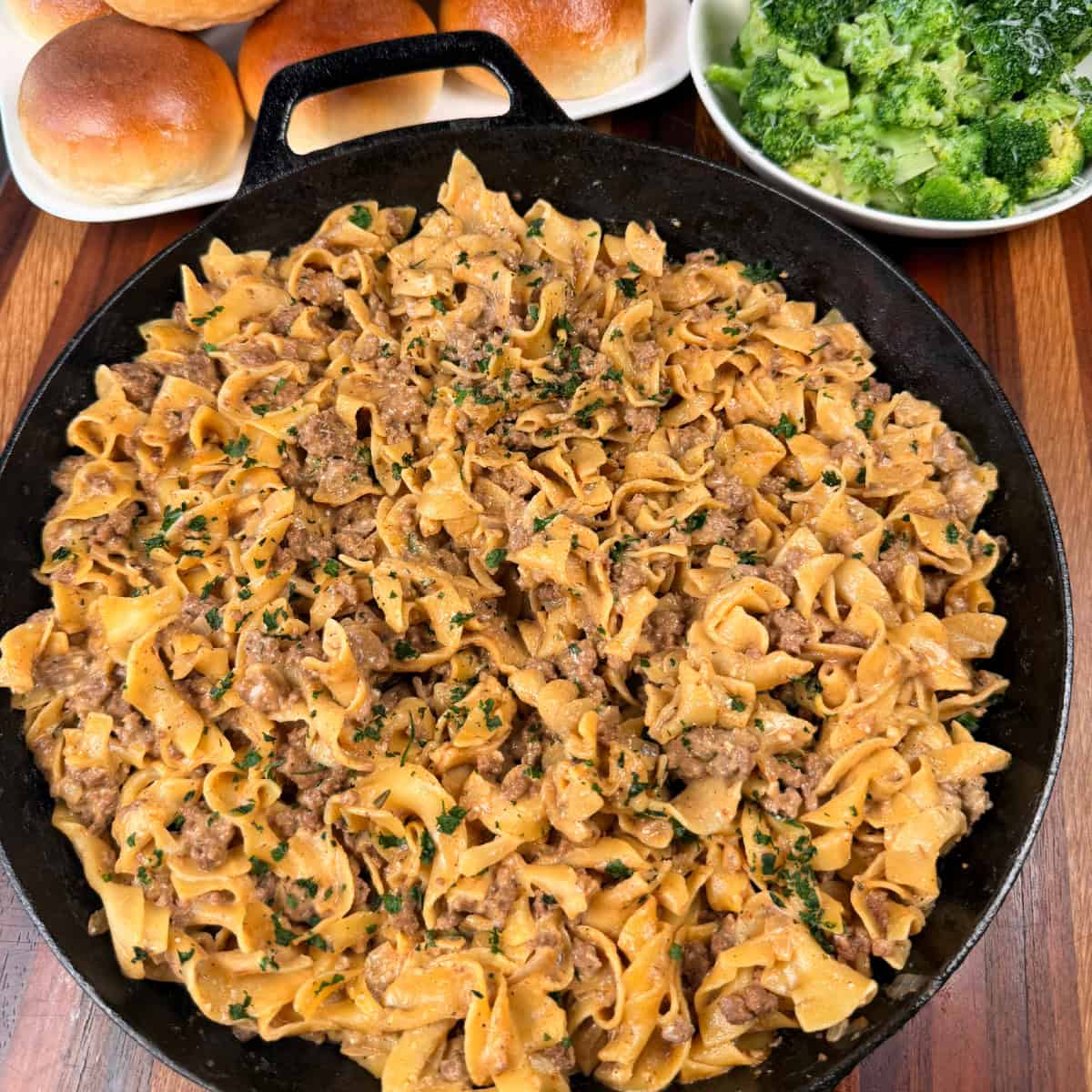 Ground Beef Stroganoff in skillet with rolls and steamed broccoli