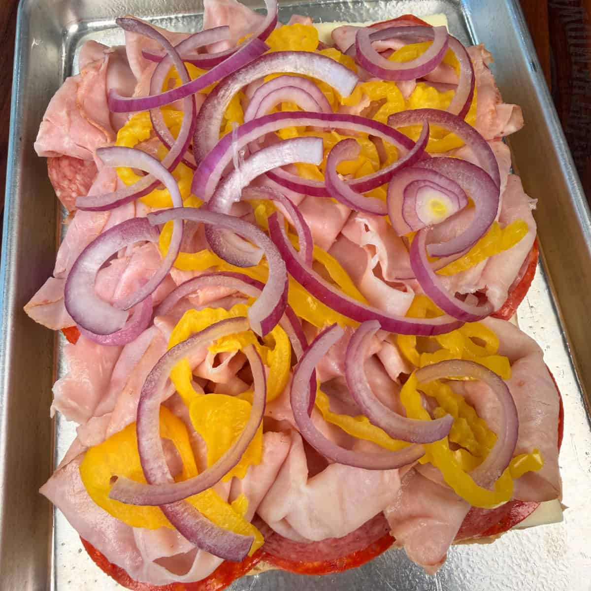 Sliders with salami, pepperoni, banana peppers, and red onion 