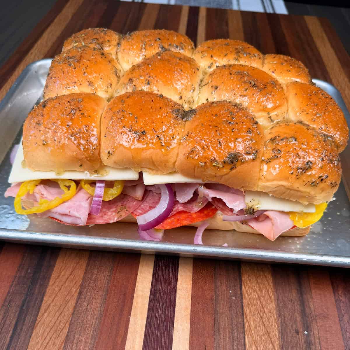 Italian slider on Hawaiian rolls and brushed with butter and seasoning on sheet pan