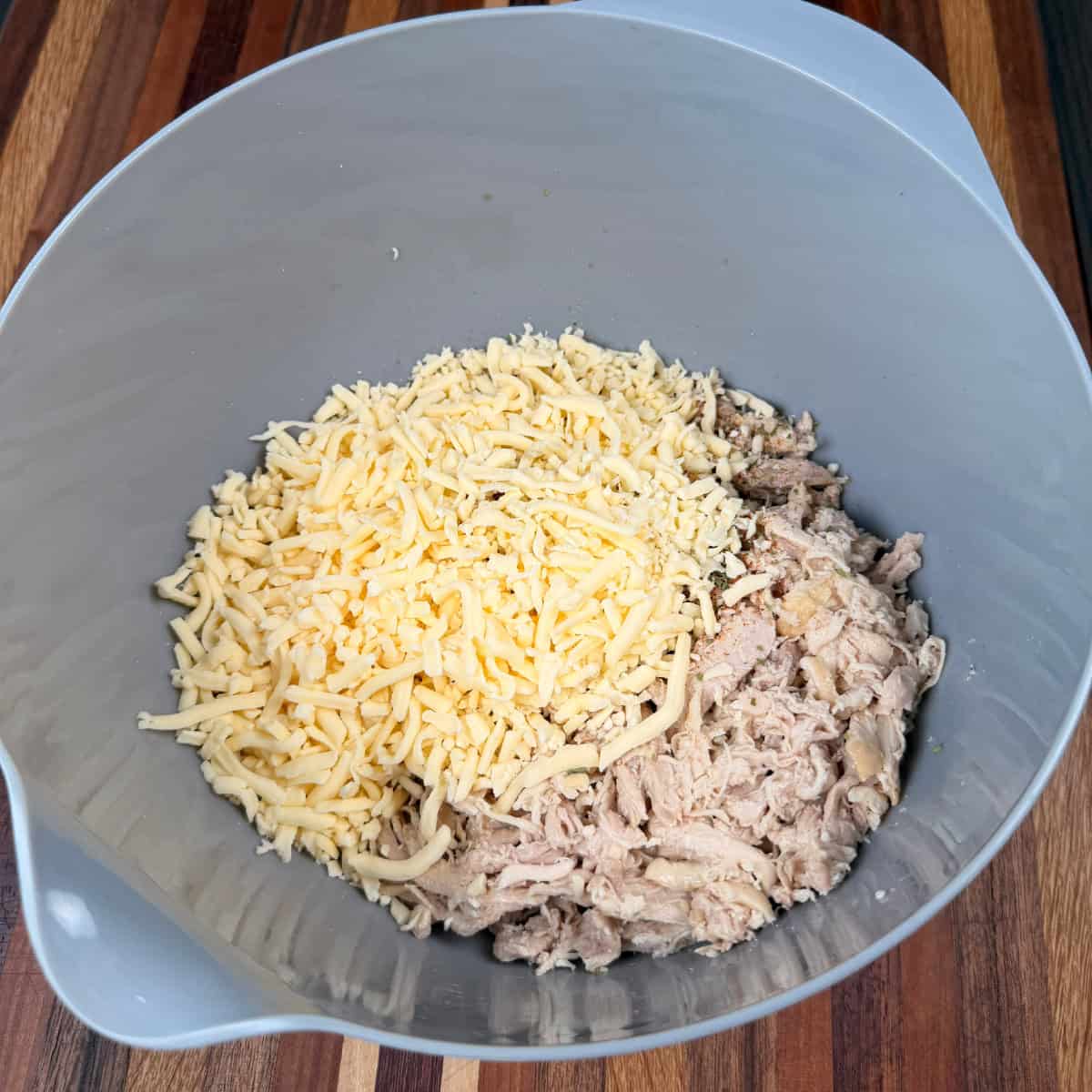 Seasoned shredded chicken with shredded cheese in a bowl