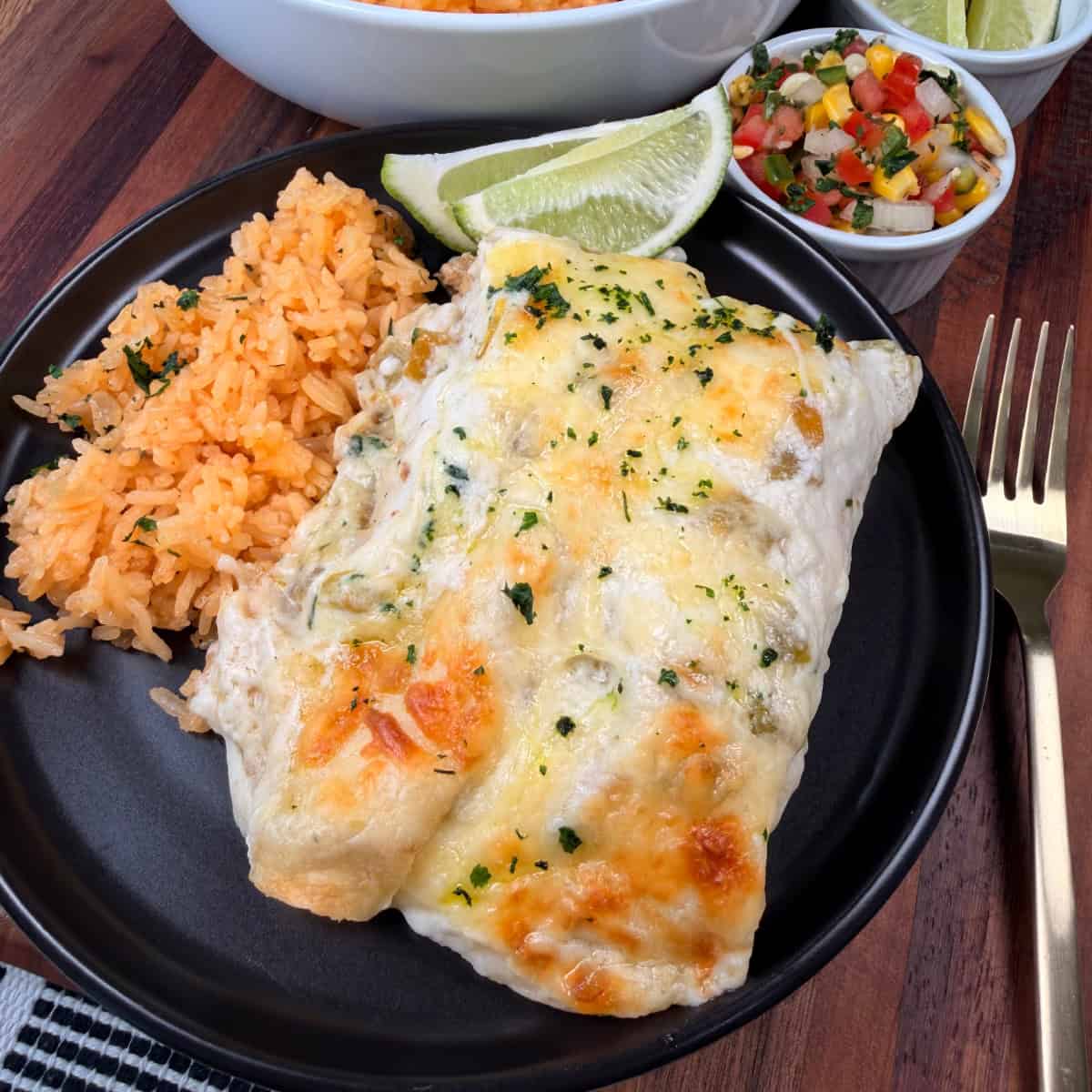 Plated White Chicken Enchiladas with rice and limes