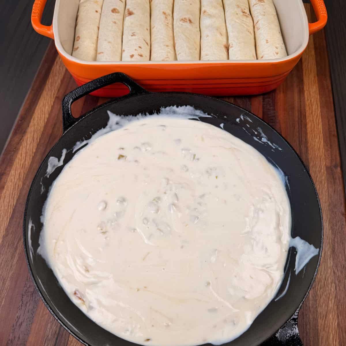 Chicken Enchiladas in a pan and white sauce in a skillet