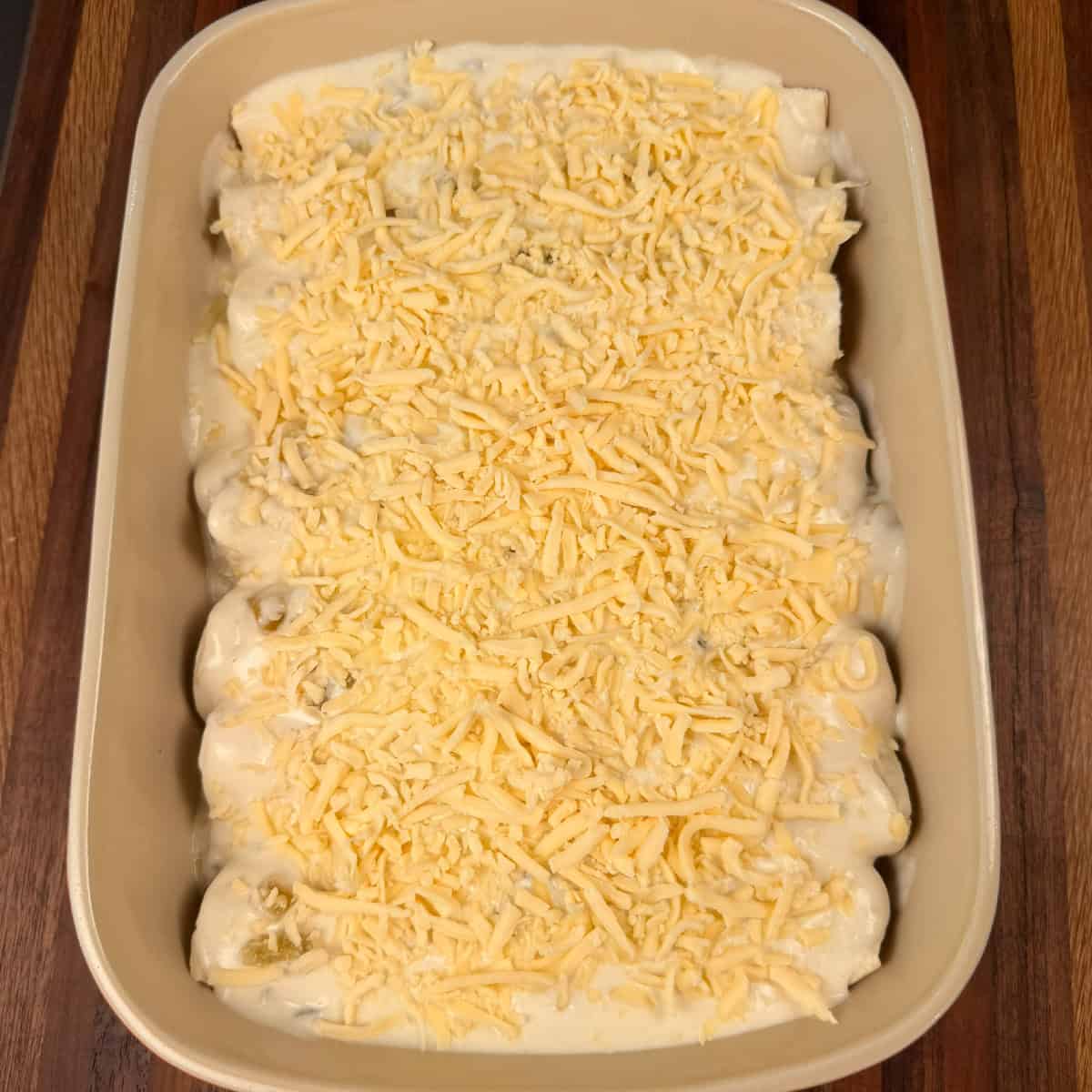 Chicken enchilada covered in white sauce and shredded cheese
