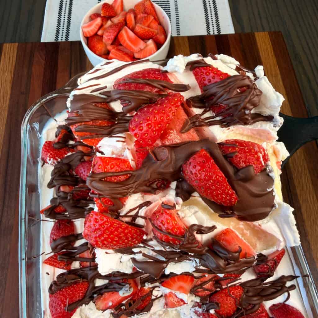 Chocolate Covered Strawberry Poke Cake Slice with a bowl of strawberries