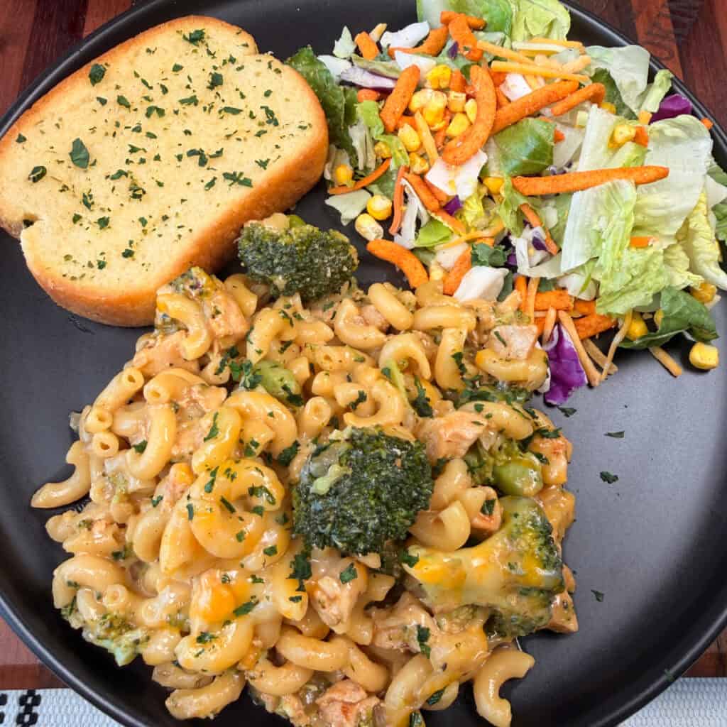 Cheesy Chicken Broccoli Mac plated with garlic toast and salad