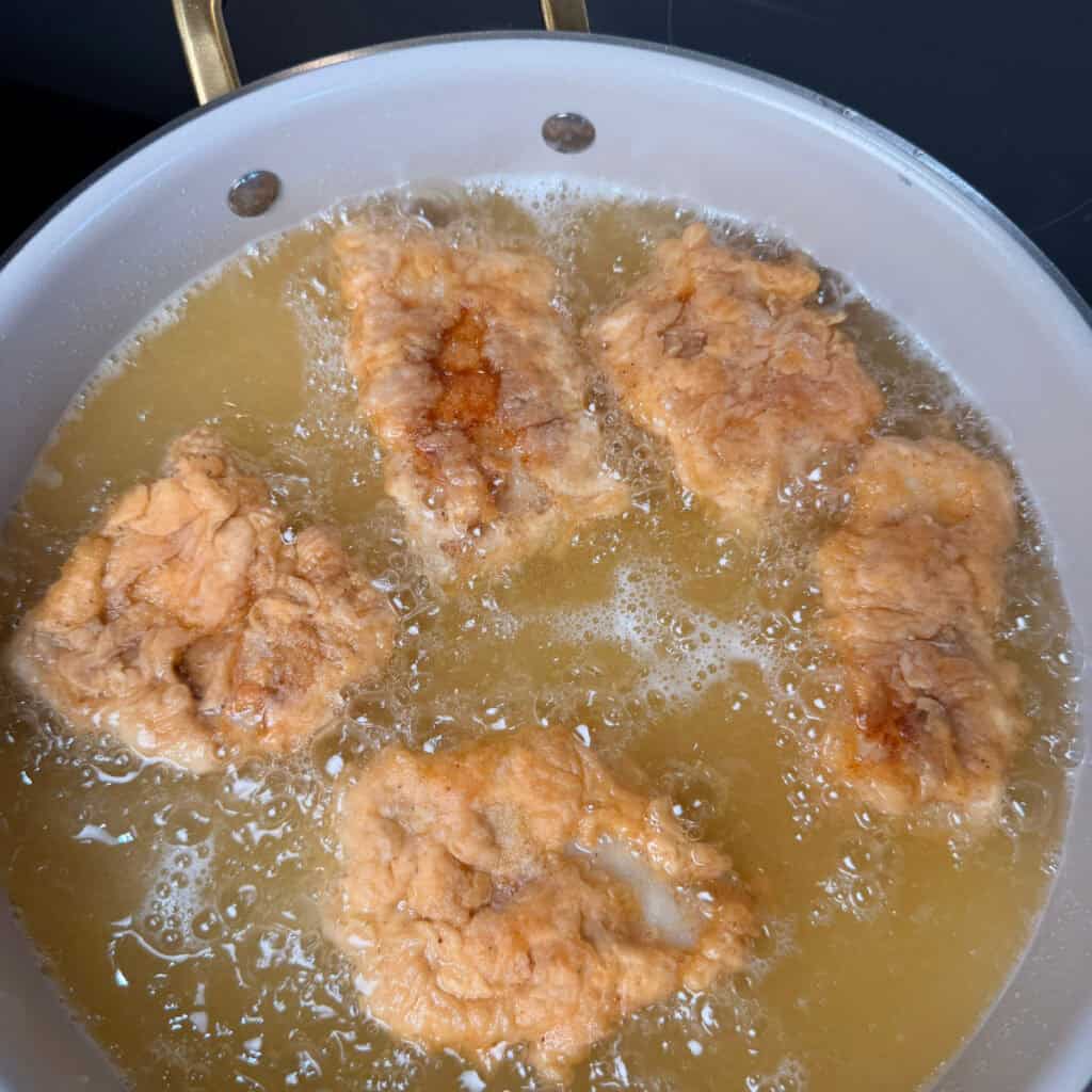 Breaded fish frying in pan of oil