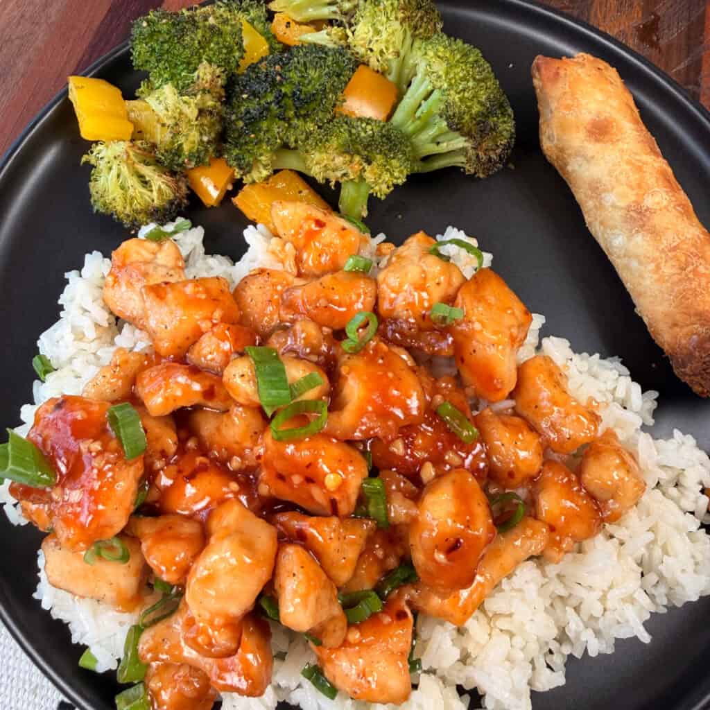 Plated Sweet and Sour Chicken with rice, veggies, and an egg roll