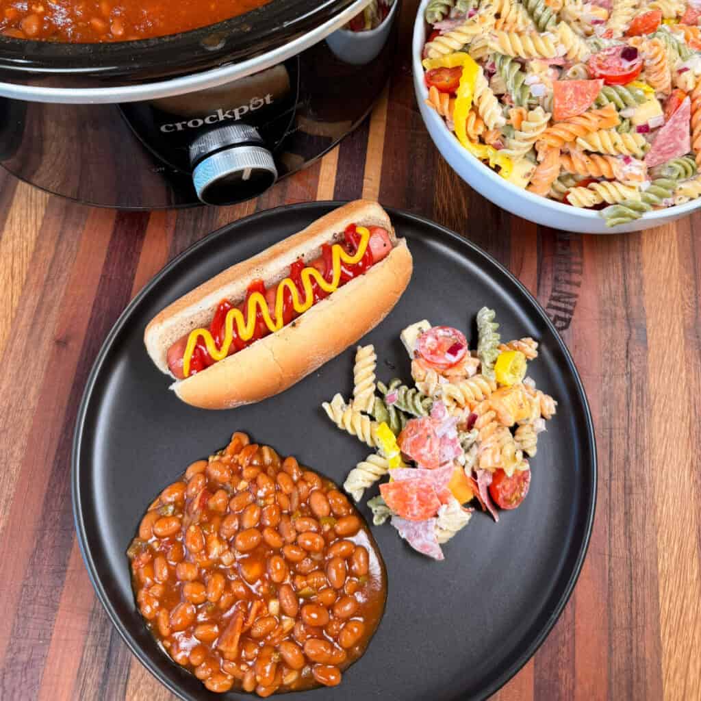 Plated Pasta salad with hot dog and baked beans