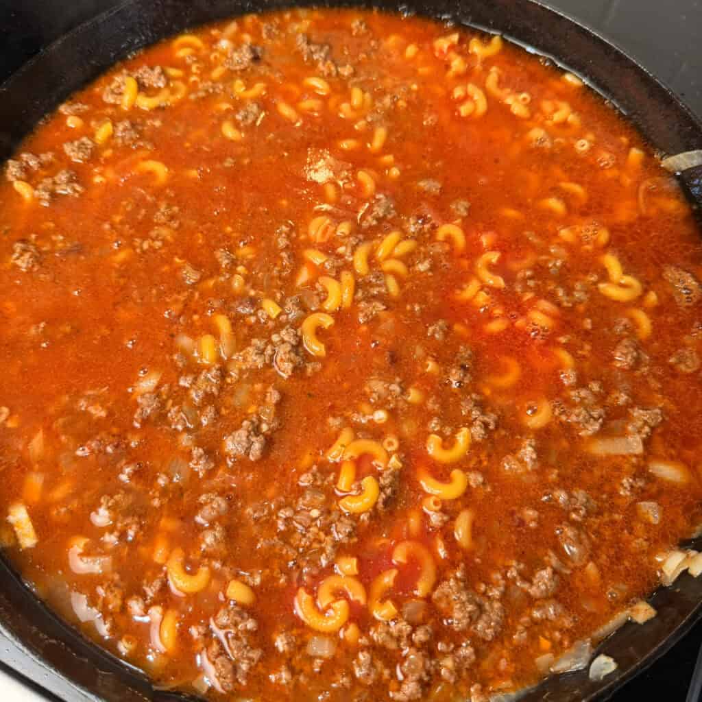 Cheeseburger Mac cooking in skillet with broth