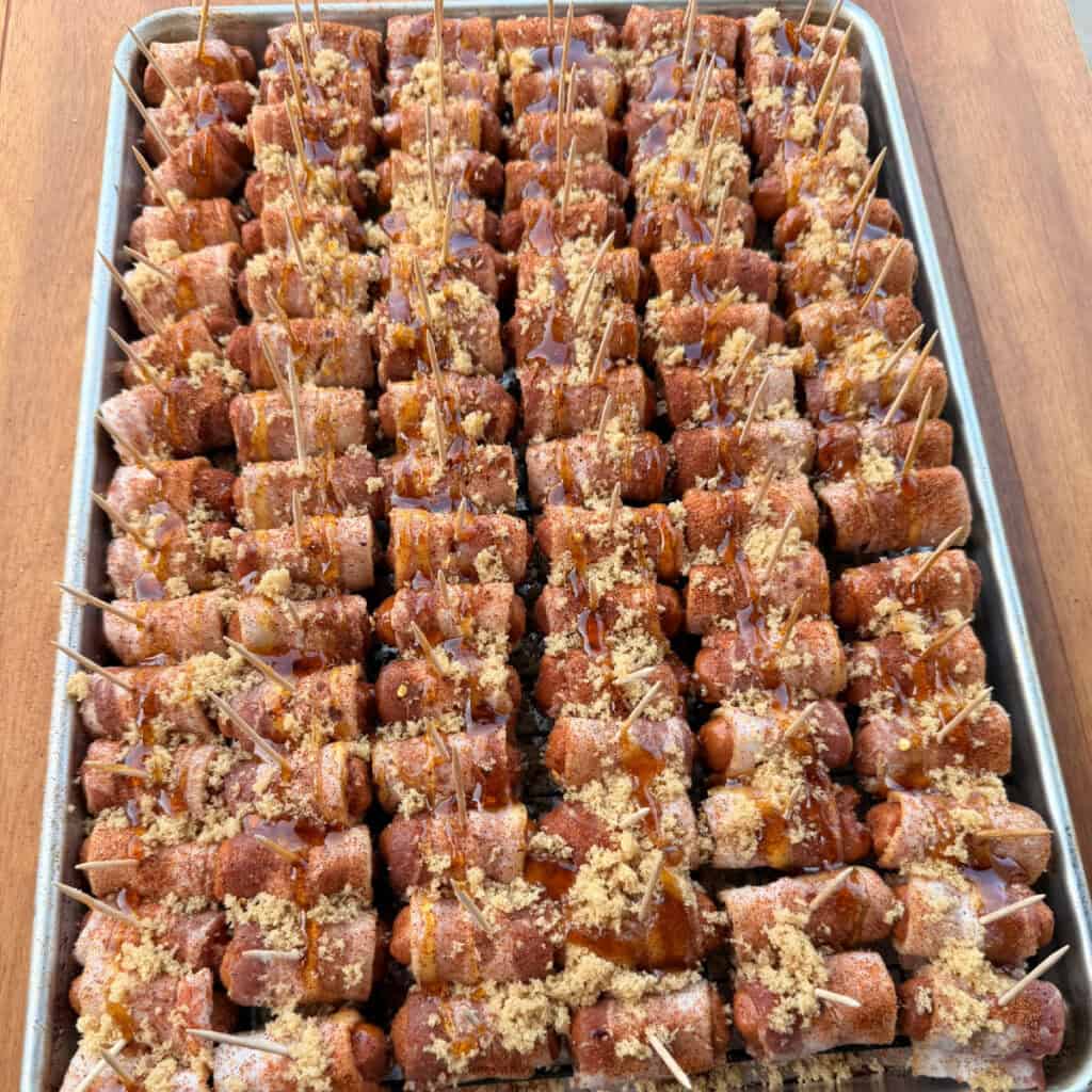 Uncooked Little Smokies on sheet pan topped with brown sugar, red pepper flakes, and hot honey