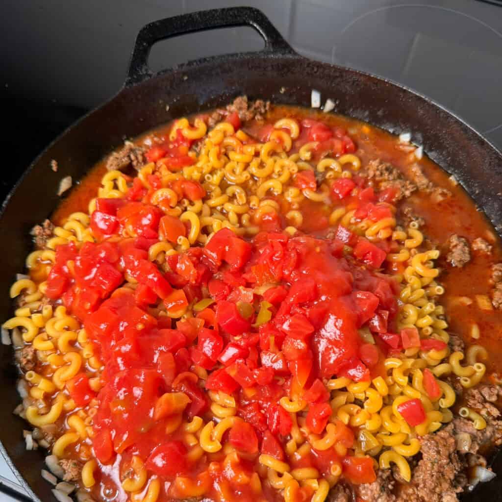 Cooking ground beef, elbow macaroni, Rotel in skillet