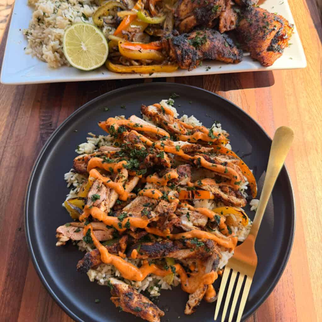 Plated Chicken Thighs, rice, peppers, onions, chipotle sauce