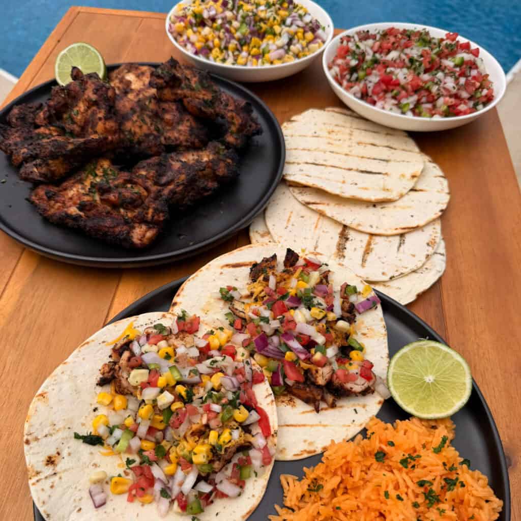 Chicken Thigh Tacos with plated Chicken, tortillas, corn salsa, and Pico de gallo