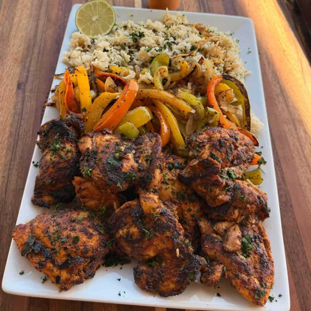 Plated Chicken Thighs, peppers, onions, and rice