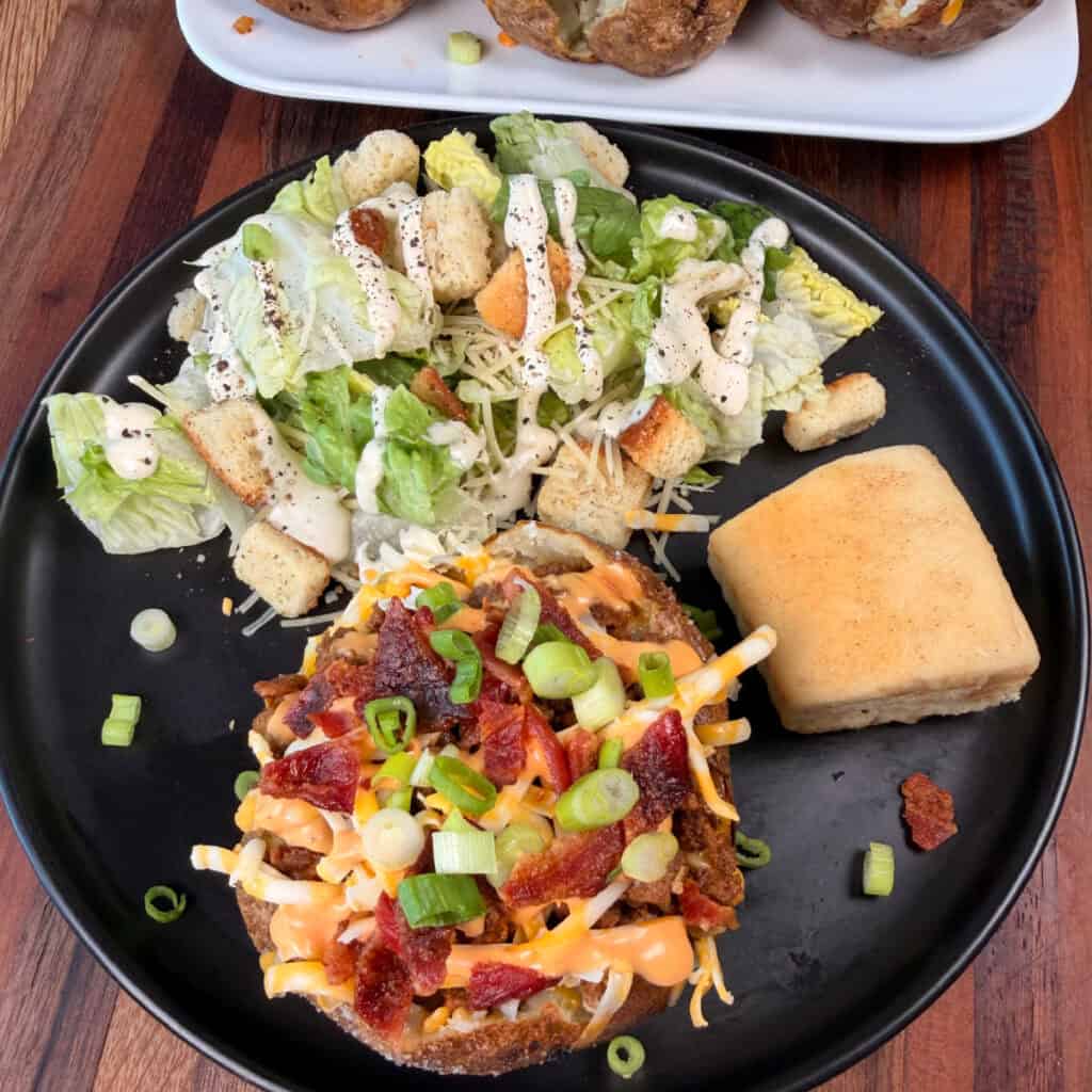 Plated Cheeseburger Baked Potatoes with salad and roll
