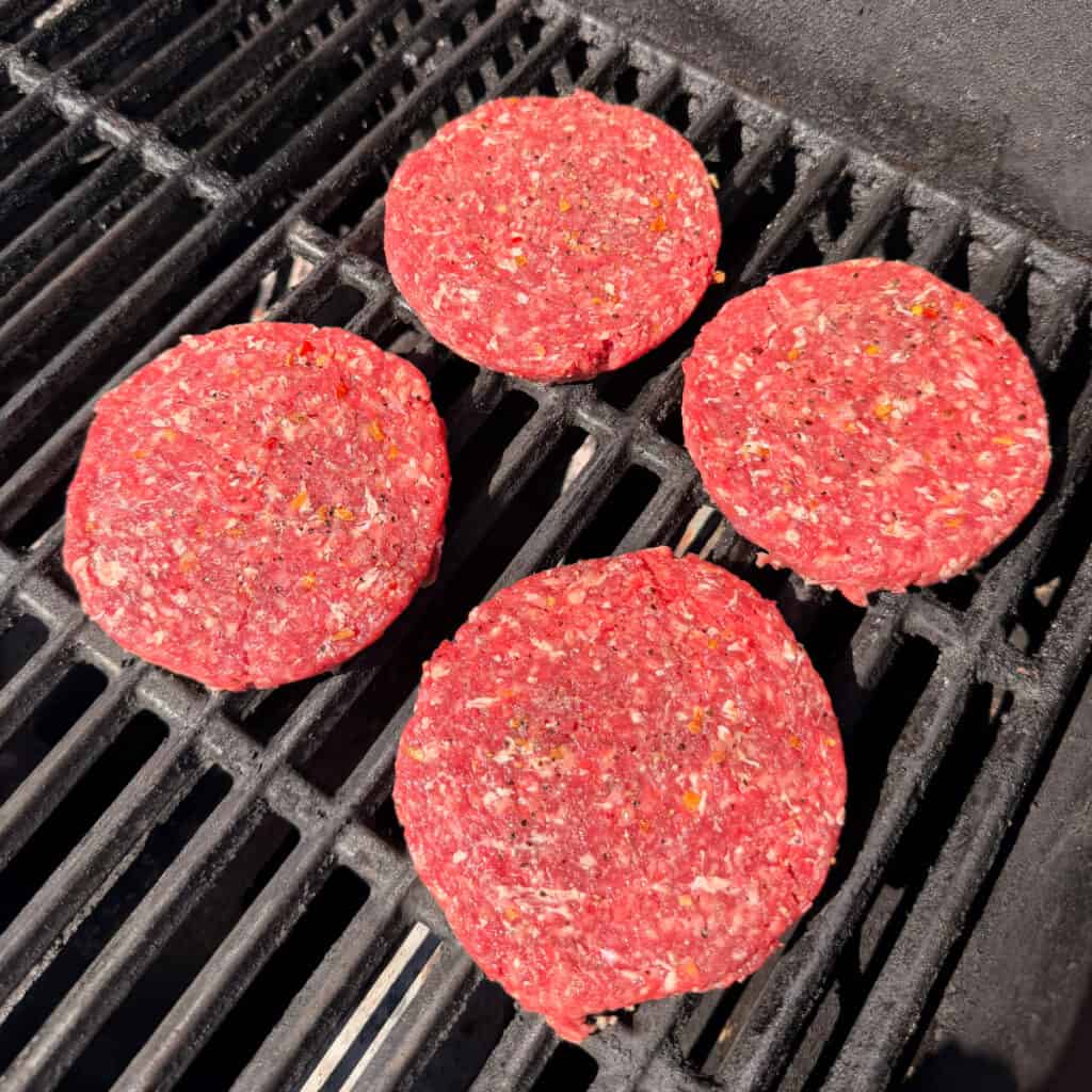 Seasoned burger patties on grill