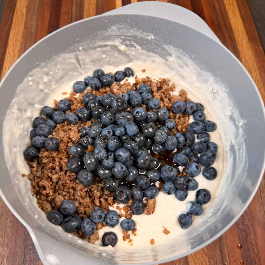 Bowl of pancake mix, browned sausage, blueberries, and syrup