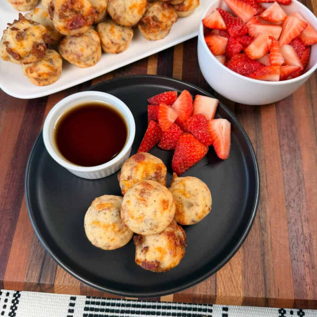 Plated mini breakfast pancake bites with syrup and cut strawberries