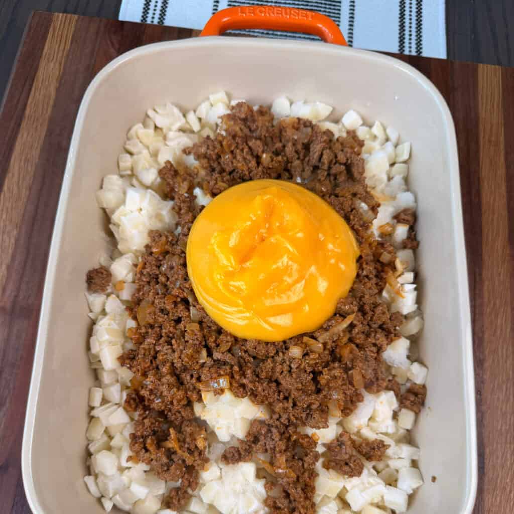 Hash browns, ground beef, and condensed cheese soup in baking dish