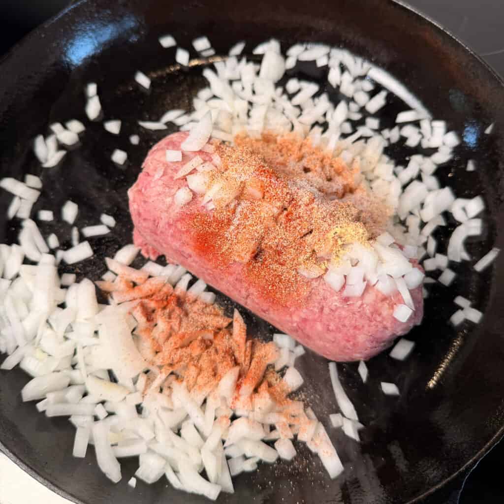 Ground beef seasoned with onions in skillet