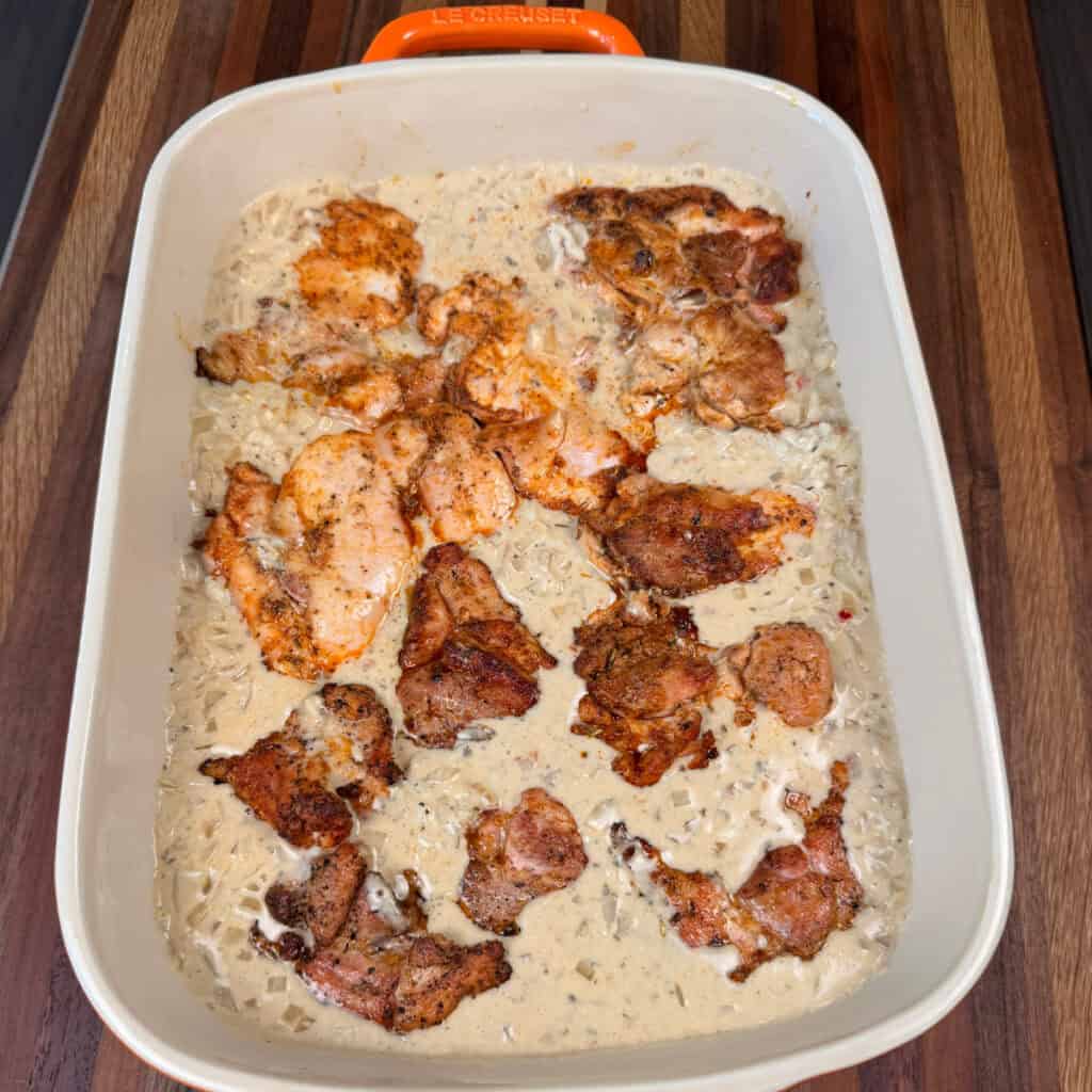 Uncooked casserole dish of rice and chicken thighs