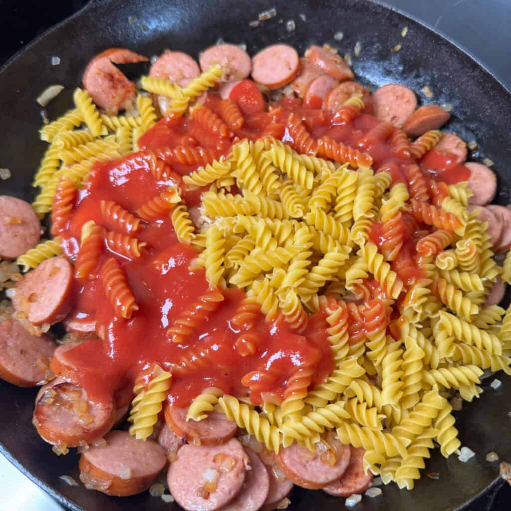 Skillet of browned kielbasa, pasta, tomato sauce, and onions