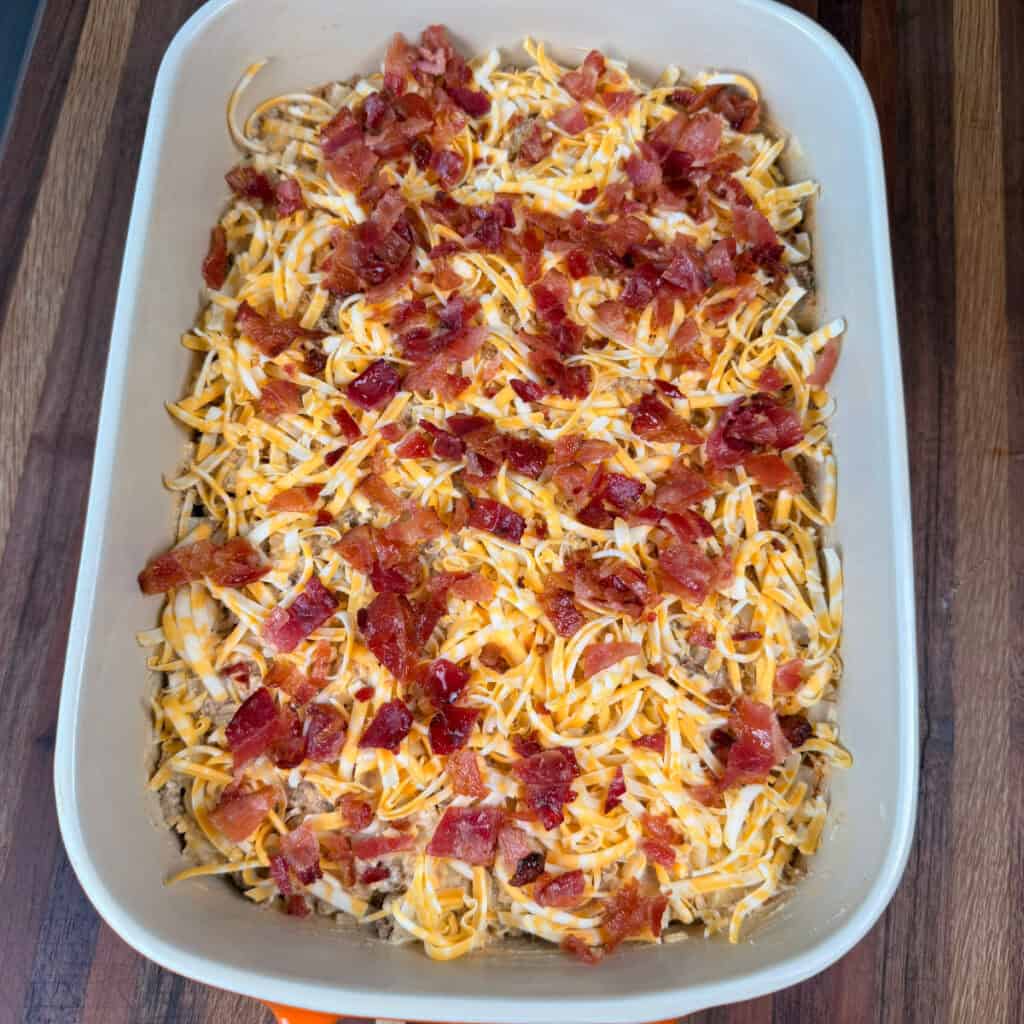 Ground Beef Potato Casserole unbaked topped with cheese and bacon