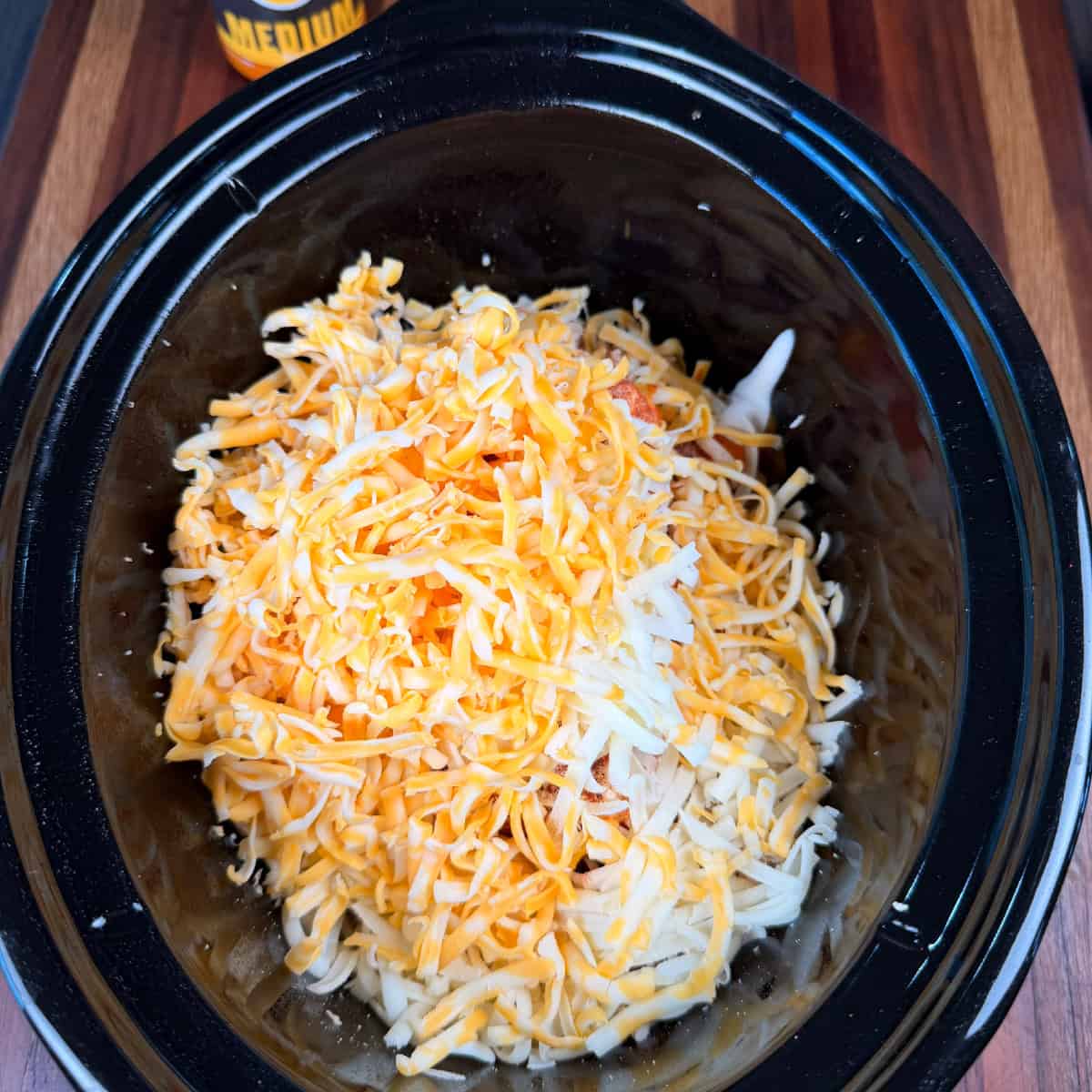 Crockpot full of shredded chicken, cream cheese, buffalo sauce, shredded Colby Jack, and shredded mozzarella cheese