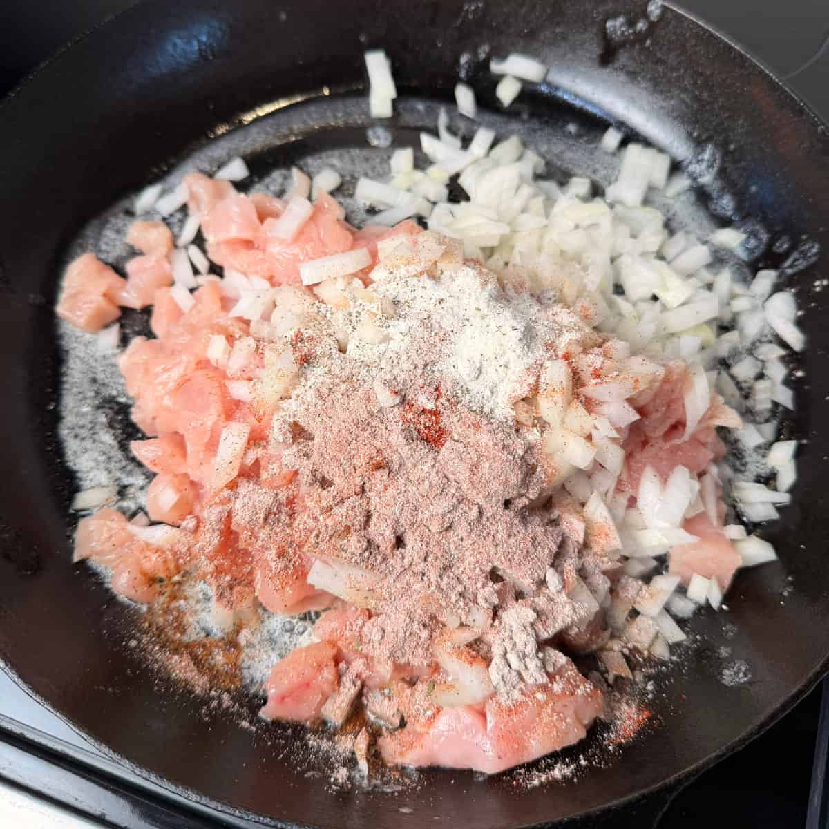 Chicken, onions, seasonings in a skillet
