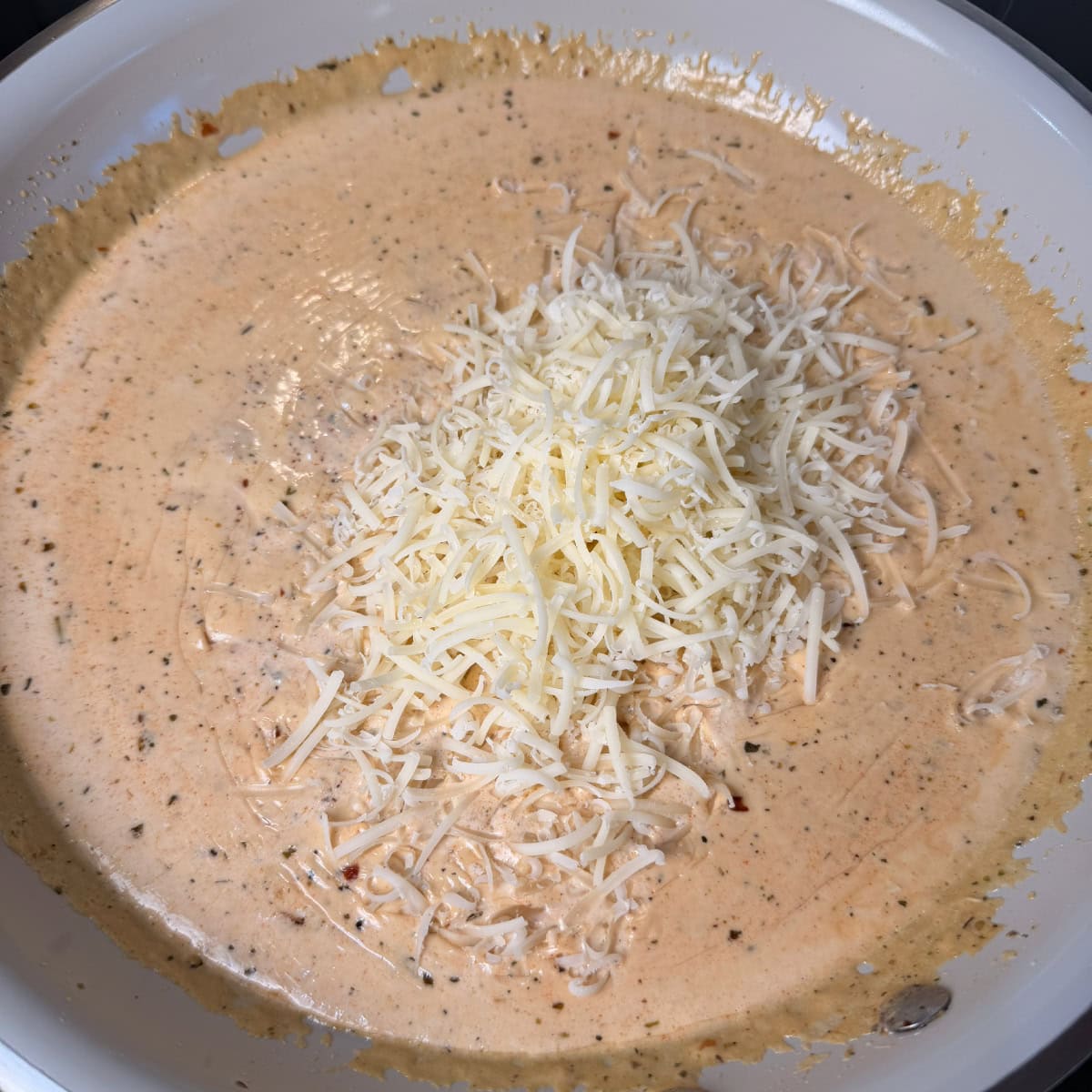 Spicy Alfredo in pan with freshly grated Parmesan cheese