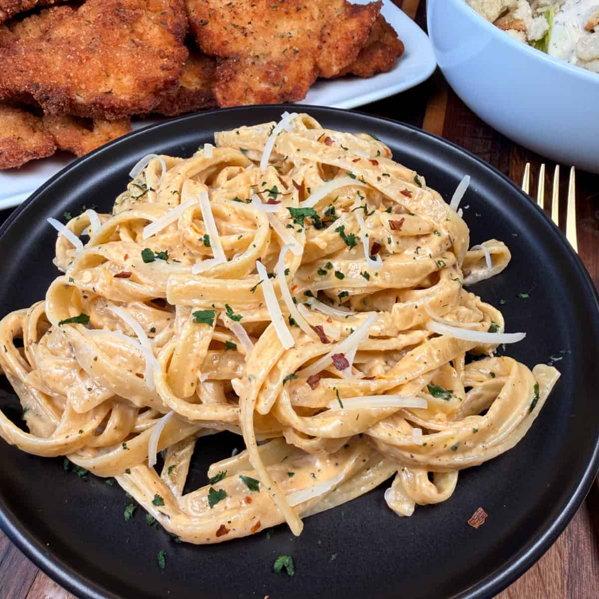Plated Spicy Alfredo Pasta with chicken cutlet and salad